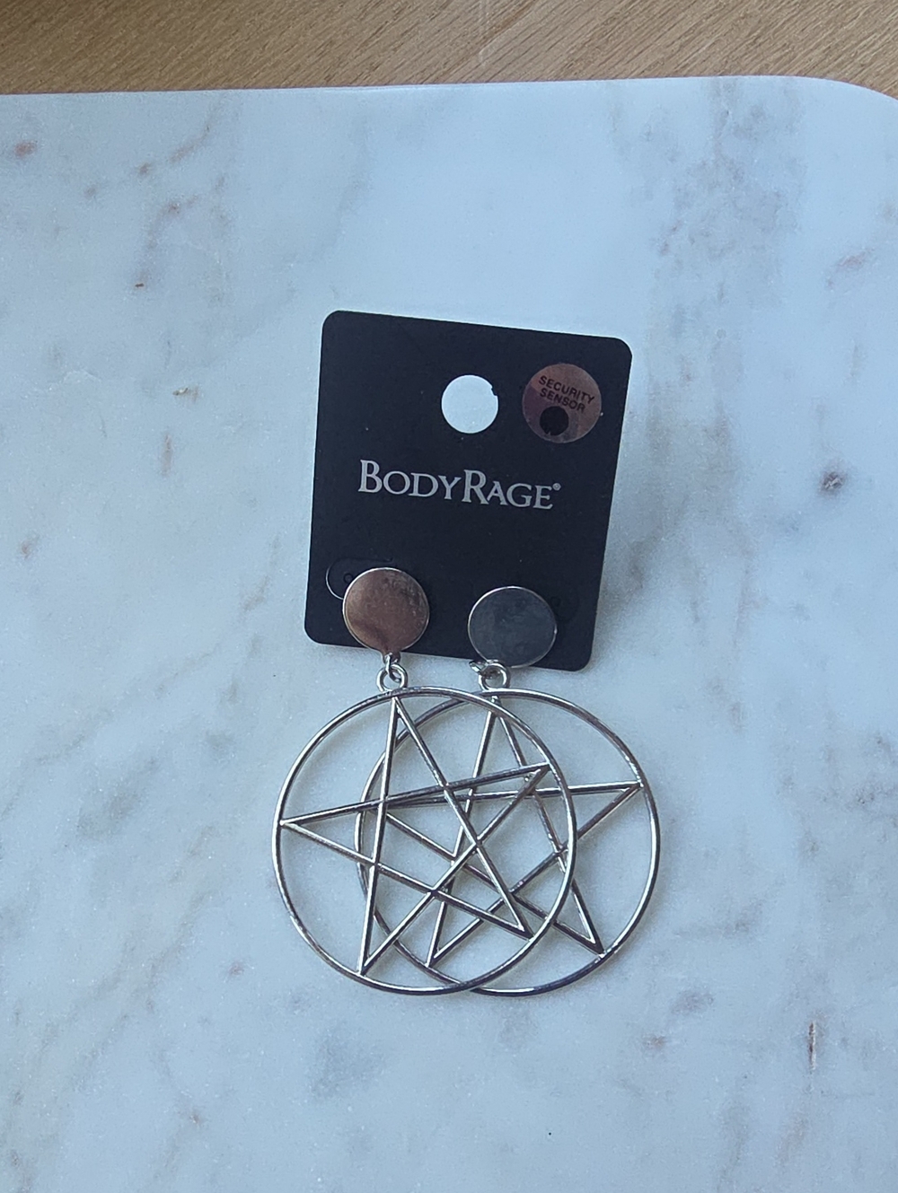 BodyRage brand earrings feature large silver-tone circle pentacle pendants.
